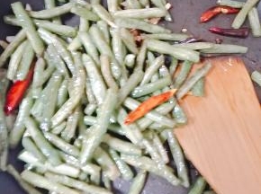放入豆角继续翻炒，加盐和鸡精调味即可。