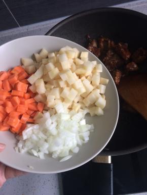 加入葱姜蒜，将所有排骨翻炒至金黄发亮后下入蔬菜丁。