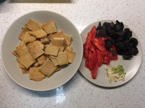 油炸豆腐切成方块，西红柿去皮切片，黑木耳泡发，葱蒜切末备用。