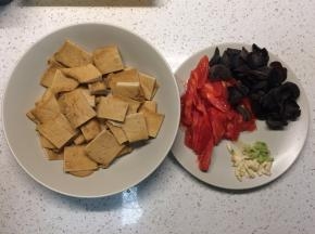 油炸豆腐切成方块，西红柿去皮切片，黑木耳泡发，葱蒜切末备用。