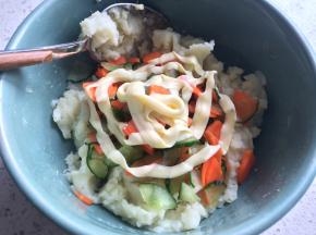 将胡萝卜和黄瓜挤掉水分放进土豆泥中，挤上沙拉酱。