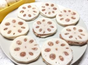 取一片莲藕放上一小勺肉馅，再盖上一片莲藕压紧，压到肉馅填满莲藕的小孔。