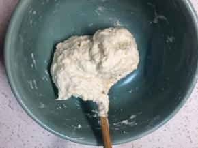 杯子里放温水，一手拿杯子一手拿筷子，一点一点往面里倒水，一边倒水一边搅拌，直到所有的面粉搅成一个面团，用筷子插着就能提起来的程度，用手稍微揉两下整成球形，盖上盖子醒30分钟。