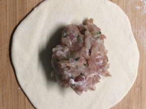 醒好的面撒上干面粉和成光滑的面团，再均匀地分成小剂子，小剂子擀成薄片后，放上之前拌好的肉馅。