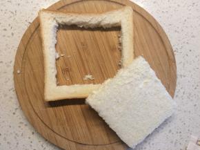 取一片吐司，用小刀在中间挖一个方形的洞，小心不要切断。火腿、黄瓜切片备用。