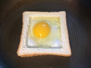 平底锅刷油，开小火，放入吐司框，打入鸡蛋。