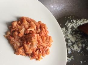 起锅爆香蒜末，下入泡菜丝炒出香味。