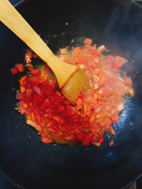 锅内倒油加入葱和辣椒炒香后倒入西红柿翻炒。