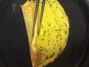 待边缘稍稍变焦，关火，用余热继续煎，小心的挑起边缘，迅速的用筷子卷起来。