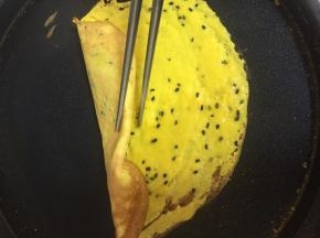 待边缘稍稍变焦，关火，用余热继续煎，小心的挑起边缘，迅速的用筷子卷起来。