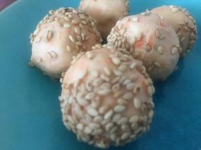 将面团在手心搓圆，拿出熟芝麻，裹在面团上。