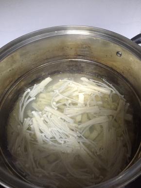 然后在锅里倒入水，煮开放入金针菇，煮3分钟