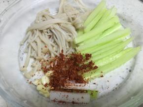 将切好的黄瓜和煮好的金针菇放入盘中，加入蒜瓣和辣椒粉