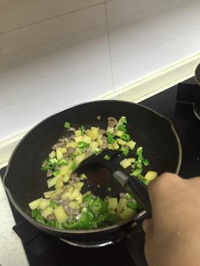 加入土豆丁，混合炒2-3分钟后加入青椒丁