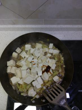 锅内白菜帮基本都软了之后加入白菜叶，加入切好的豆腐