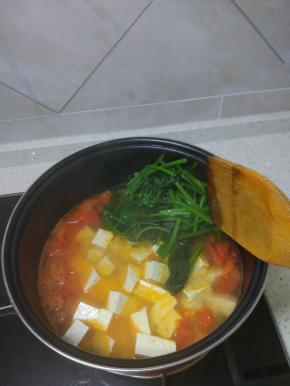 待西红柿炒至软烂之后加入热水，一次加入菠菜，豆腐