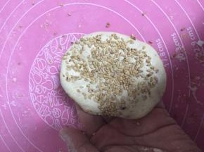 将面团分成小块，压扁成饼状，放上芝麻