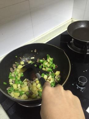 加入土豆丁，混合炒2-3分钟后加入青椒丁