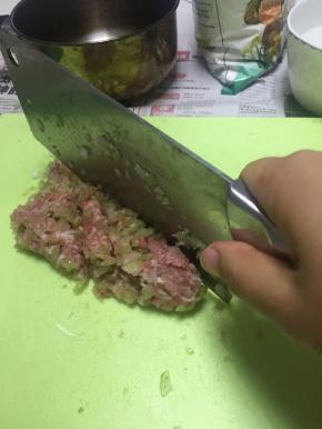 将芹菜丁加入肉糜中，切匀