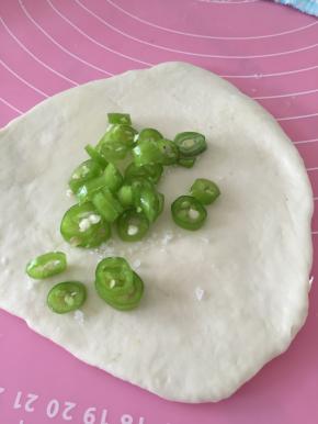 将面团擀开，加上少量盐和橄榄油，盐作为调味可充解青椒的辣味，橄榄油可使薄饼更加酥脆。将油和盐抹匀，加上青椒