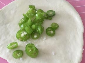 将面团擀开，加上少量盐和橄榄油，盐作为调味可充解青椒的辣味，橄榄油可使薄饼更加酥脆。将油和盐抹匀，加上青椒