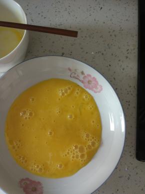 打散的鸡蛋倒入盘子里面，盘子一定要能放的下去一整片吐司的大小