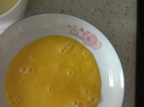 打散的鸡蛋倒入盘子里面，盘子一定要能放的下去一整片吐司的大小