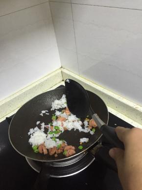 加入米饭，一起翻炒，使得米饭被炒好的香肠涂抹均匀，翻炒3-5分钟，加入鲜酱油