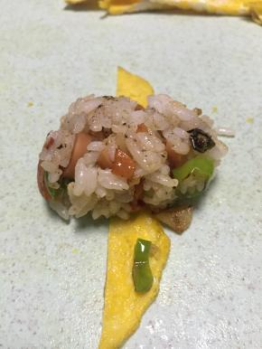 拿出炒好的饭，捏成长条团子，用蛋饼条卷好