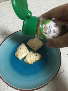 将豆腐煎的双面金黄，放入盘子里，依据自己的口味加入花椒粉、孜然粉、辣椒粉、盐