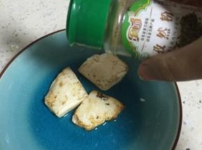 将豆腐煎的双面金黄，放入盘子里，依据自己的口味加入花椒粉、孜然粉、辣椒粉、盐
