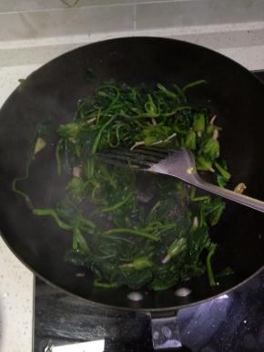 锅内热油爆香葱姜蒜加入控干水分的菠菜