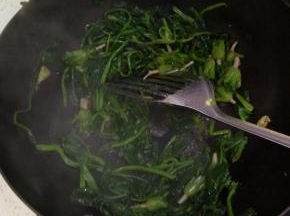 锅内热油爆香葱姜蒜加入控干水分的菠菜