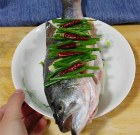 铺一层姜片葱段在盘底，鱼肚内塞入姜片，放入蒸锅内蒸5分钟，倒去汁液，淋上蒸鱼鼓油，将葱姜均匀铺满鱼，依照个人喜好加入干辣椒