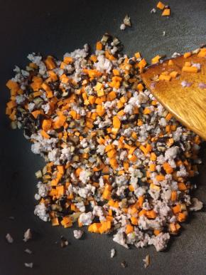 等面团发酵的时间可以来炒內馅，热锅凉油下肉糜小火炒至出油后，下入香菇丁和胡萝卜丁继续翻炒。