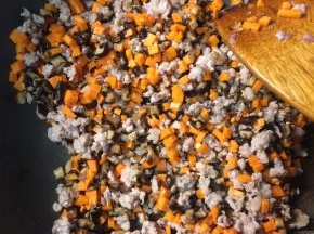 等面团发酵的时间可以来炒內馅，热锅凉油下肉糜小火炒至出油后，下入香菇丁和胡萝卜丁继续翻炒。