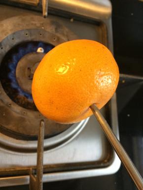 拿一个新鲜的桔子，取一根筷子从桔子中间的凹陷处插入，燃气灶开最小火，将桔子放在火上烤，不断旋转让桔子均匀受热。