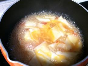 番茄汤底煮开后，一手拿起长条面片，另一手将其揪成约5cm的面片下入锅中，用筷子轻轻搅拌