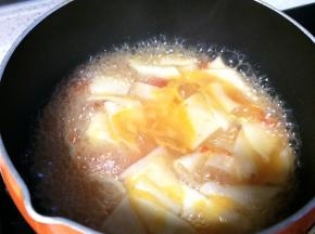 番茄汤底煮开后，一手拿起长条面片，另一手将其揪成约5cm的面片下入锅中，用筷子轻轻搅拌