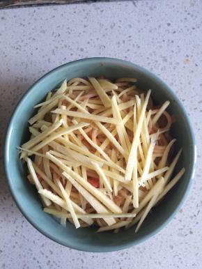 将炒好的意面装入烤碗，撒上芝士条