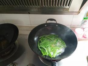 等到辣椒翻炒至有些干瘪后，再倒入少许水，盖上锅盖