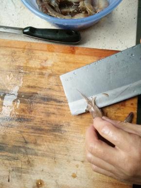 用菜刀将虾从中间剖开，从头一直到尾部，尾部不能全部剖开