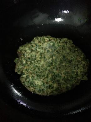 锅内放入适量油，把搅拌均匀的韭菜放入锅中，用铲子摊开