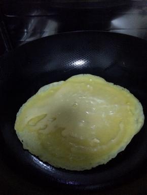 锅内放底油烧至七成热，慢慢转动锅，使油在锅边均匀。把搅拌好的面粉放入锅中。