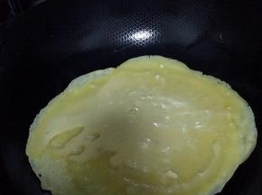 锅内放底油烧至七成热，慢慢转动锅，使油在锅边均匀。把搅拌好的面粉放入锅中。