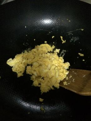 锅内放入适量油，把鸡蛋放入锅内翻炒成快状。