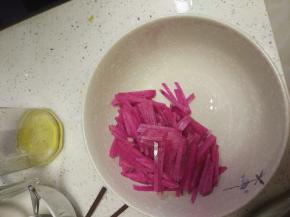 红心萝卜切丝，放入碗内