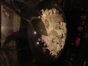 把白菜放进锅里翻炒，适量加入味达美。