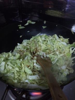 锅内加入适量的油，放入葱花等调料，把卷心菜放入锅中翻炒。