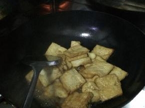 把炸好的豆腐块放入锅内加入适量的葱，加入少许的水。